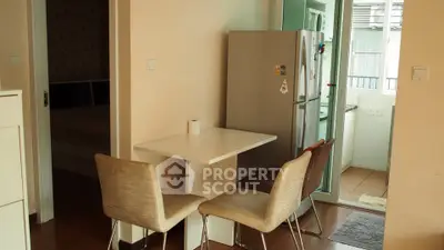 Cozy dining area with modern chairs and fridge in a compact apartment setting.