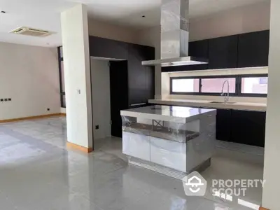 Modern kitchen with sleek black cabinets and central island in spacious open layout.