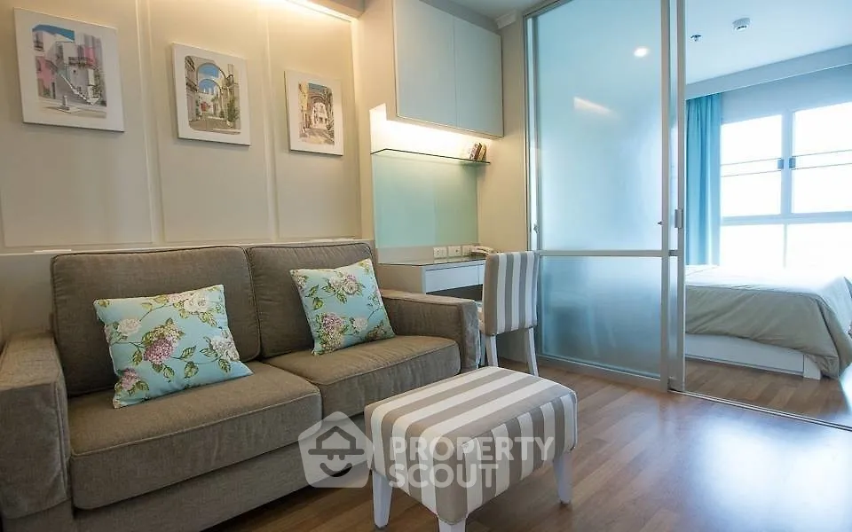 Modern apartment interior with cozy living room and bedroom separated by glass partition.