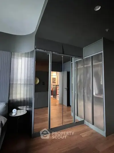 Modern bedroom with sleek mirrored wardrobe and stylish wooden flooring.