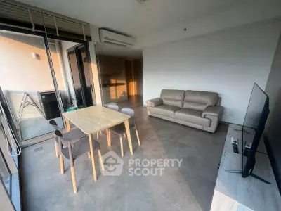Modern living room with sleek furniture and large windows opening to a balcony.