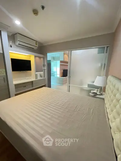 Modern bedroom with built-in TV and air conditioning, featuring a frosted glass partition.