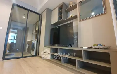Modern living room with sleek TV unit and glass sliding door to laundry area.