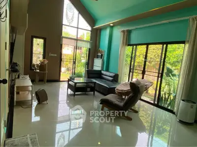 Spacious living room with high ceilings and garden view, featuring modern furniture and abundant natural light.