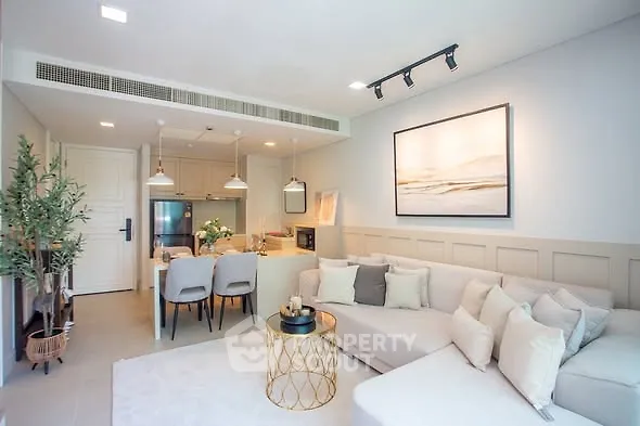 Modern living room with open kitchen, stylish decor, and cozy seating area.