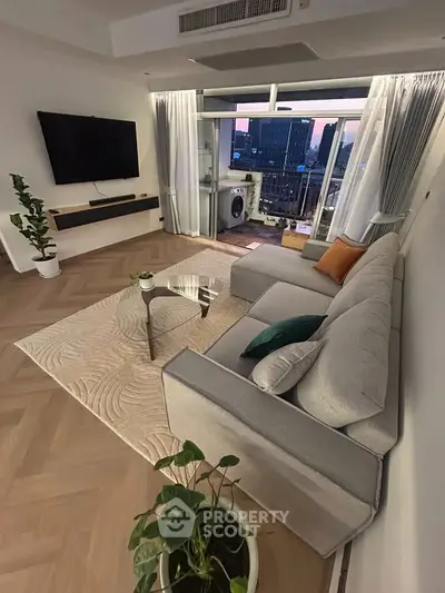 Modern living room with balcony view, stylish furniture, and cityscape backdrop.