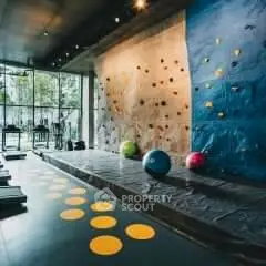 Modern gym with climbing wall and exercise equipment in luxury apartment building.