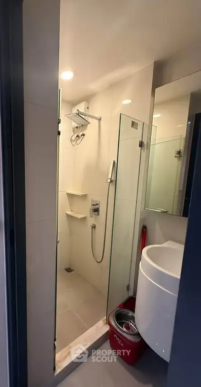 Modern compact bathroom with glass shower enclosure and sleek fixtures.