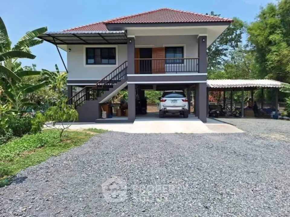 Charming two-story house with carport and lush greenery, perfect for serene living.