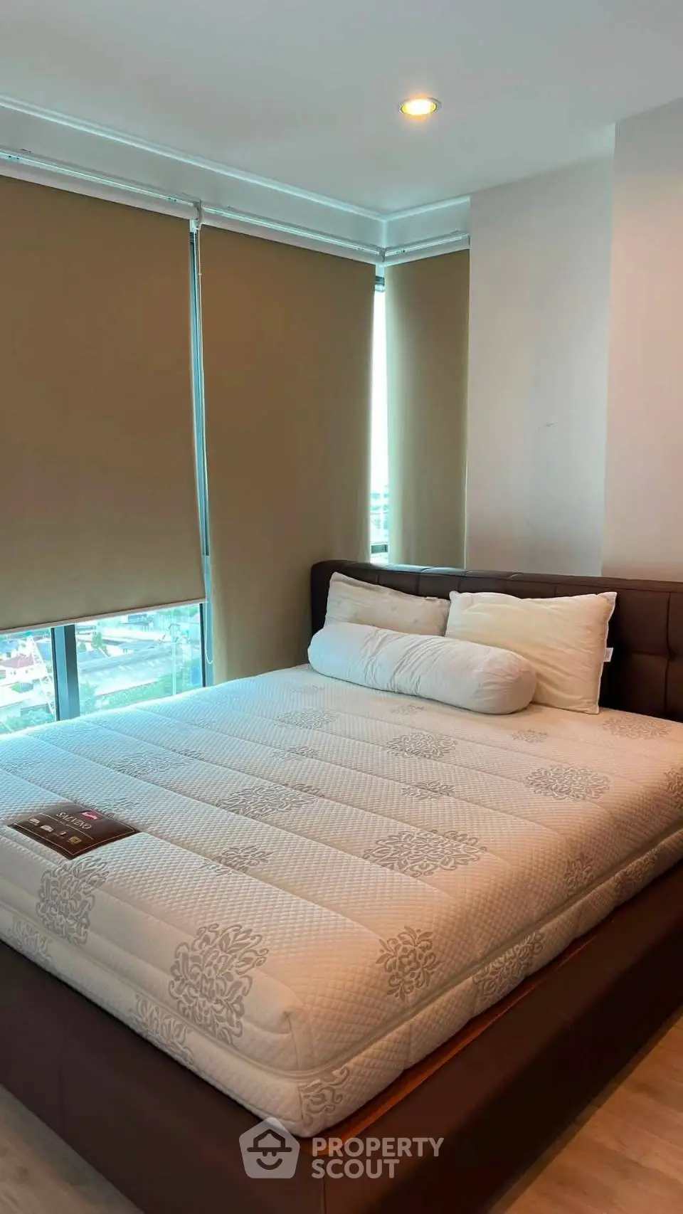 Spacious bedroom with large windows and modern furnishings in a high-rise apartment.