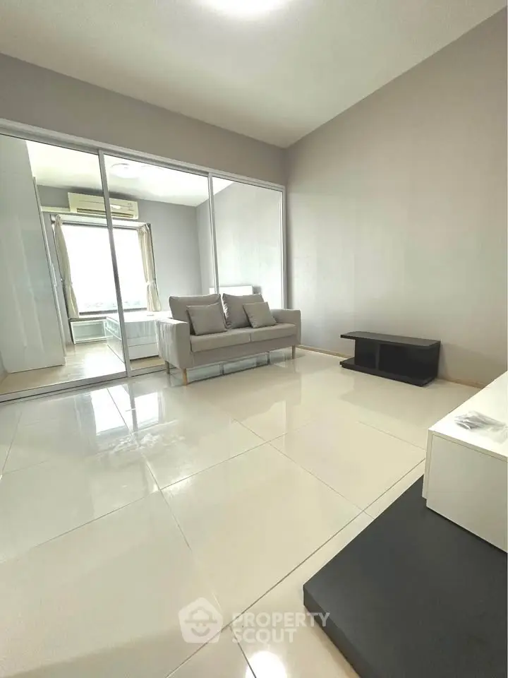 Modern living room with sleek tile flooring and mirrored closet doors, featuring a cozy sofa and minimalist decor.