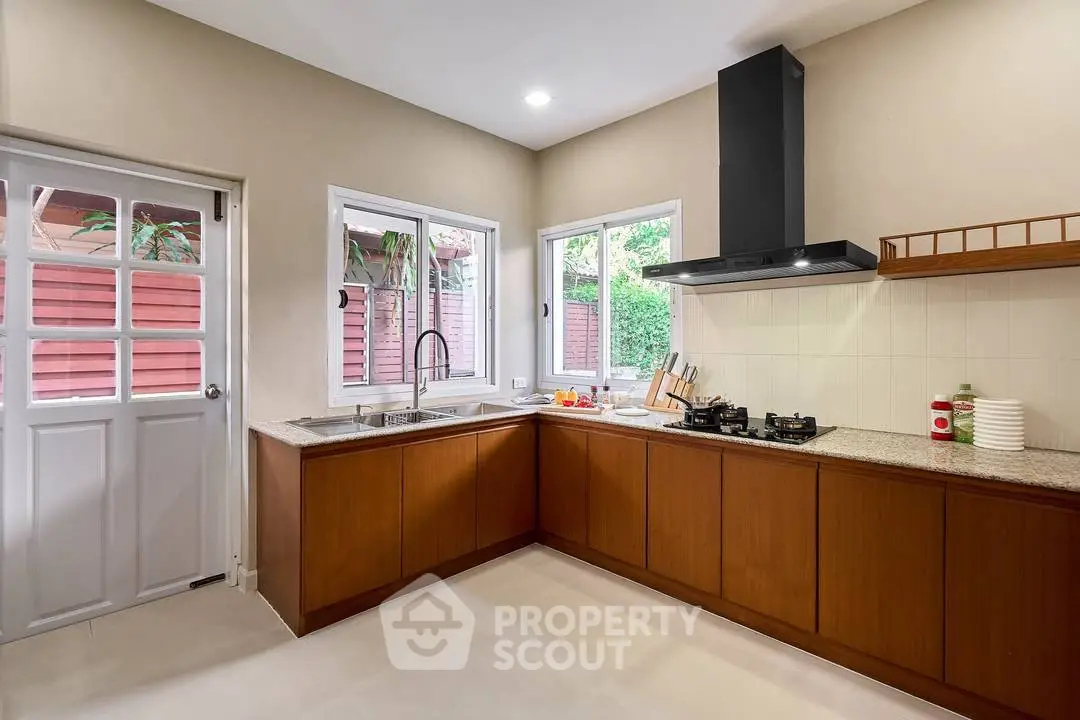Spacious kitchen with modern gas stove and ample natural light, perfect for culinary enthusiasts.