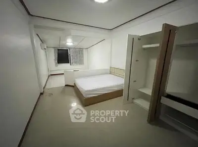 Spacious minimalist bedroom with built-in wardrobe and large window for natural light.