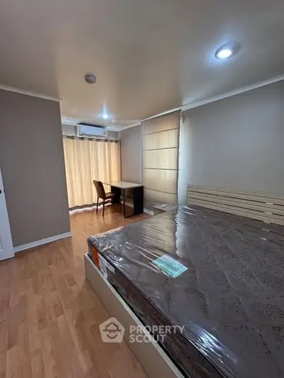 Spacious bedroom with wooden flooring and natural light