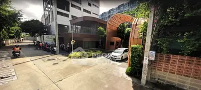 Modern building entrance with unique architectural design and lush greenery