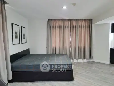 Spacious bedroom with modern decor and large windows for natural light.