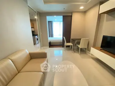 Modern open-plan living room with beige sofa and dining area in a stylish apartment.