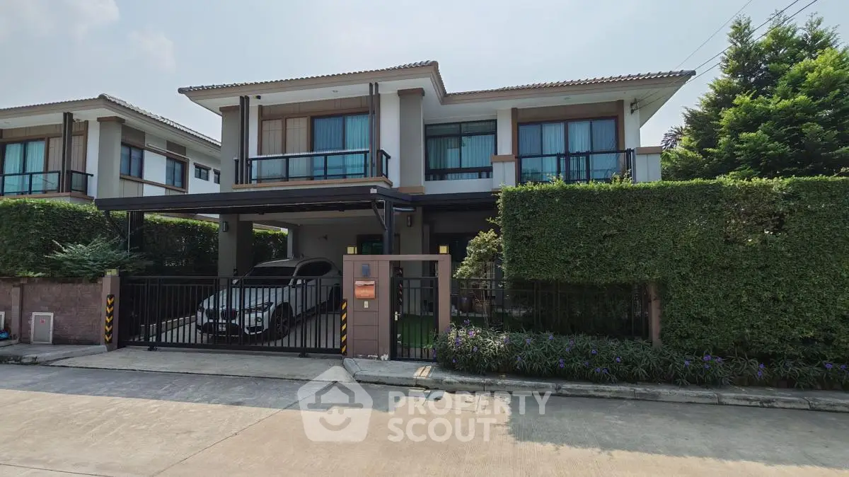 Modern two-story house with carport and lush greenery in a serene neighborhood.