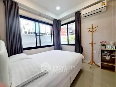Cozy bedroom with large windows and air conditioning, perfect for relaxation.