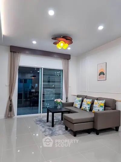 Modern living room with stylish decor, featuring a cozy sofa, elegant lighting, and a sliding glass door leading to a balcony.