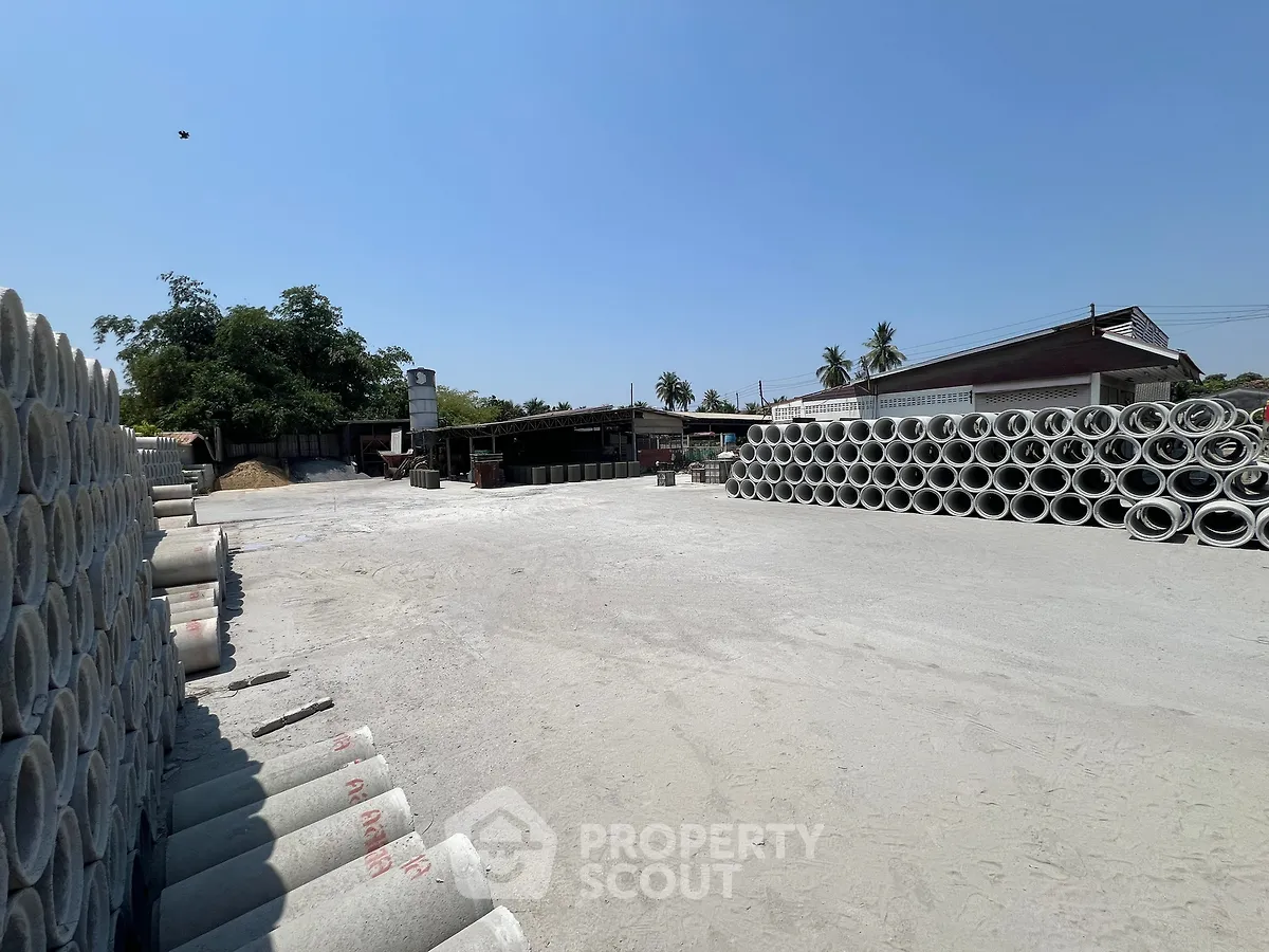 Expansive industrial property with ample outdoor storage space and stacked concrete pipes.