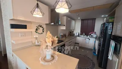 Modern kitchen with sleek design, featuring open layout and stylish lighting fixtures.