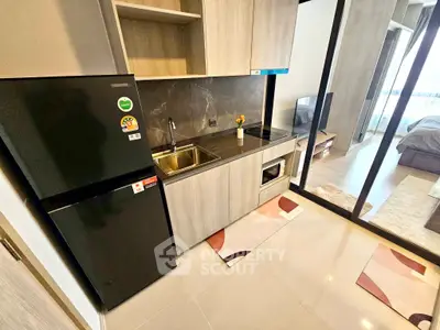 Modern kitchen with sleek design and open layout, featuring a black fridge and built-in microwave.