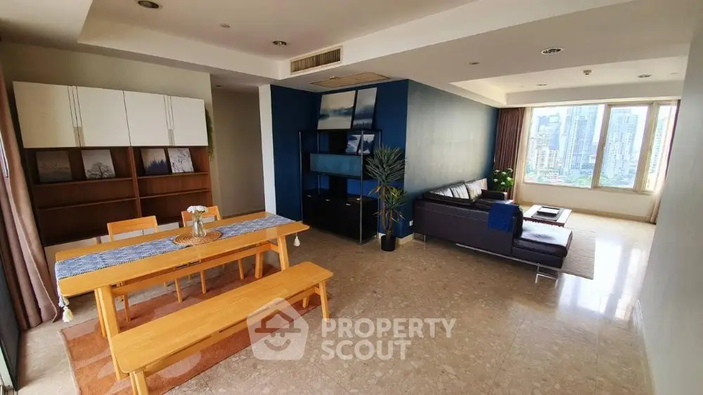 Spacious living room with dining area and city view, featuring modern furniture and natural light.