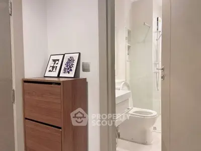 Modern bathroom with wooden cabinet and framed art, featuring sleek fixtures and neutral tones.
