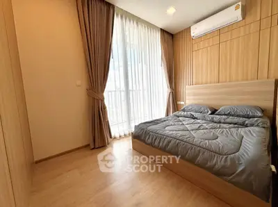 Modern bedroom with wooden flooring and large window with curtains