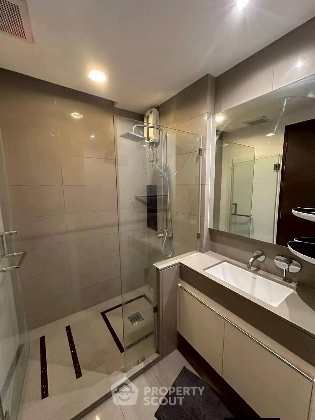 Modern bathroom with glass shower and sleek vanity in contemporary apartment.