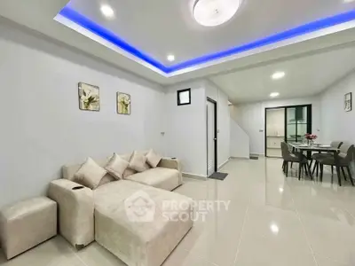 Modern living room with elegant sofa and dining area, featuring sleek lighting and minimalist decor.