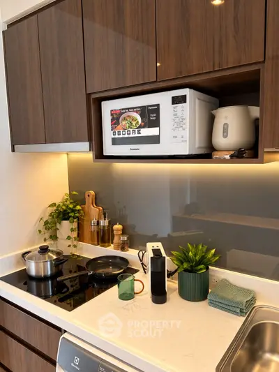 Modern kitchen with sleek cabinetry, microwave, and stylish countertop appliances.