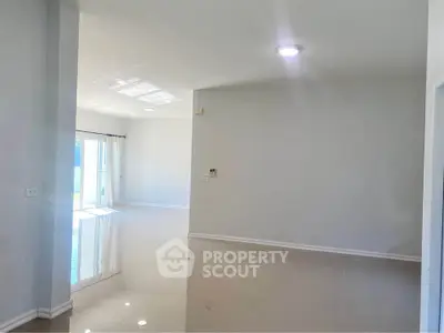 Spacious and bright empty room with glossy tiled floors and large windows.