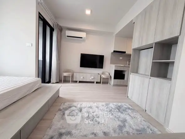 Modern studio apartment with sleek design, featuring a cozy living area, built-in storage, and a compact kitchen.