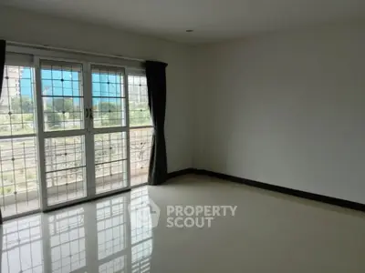 Spacious unfurnished room with large windows and balcony view
