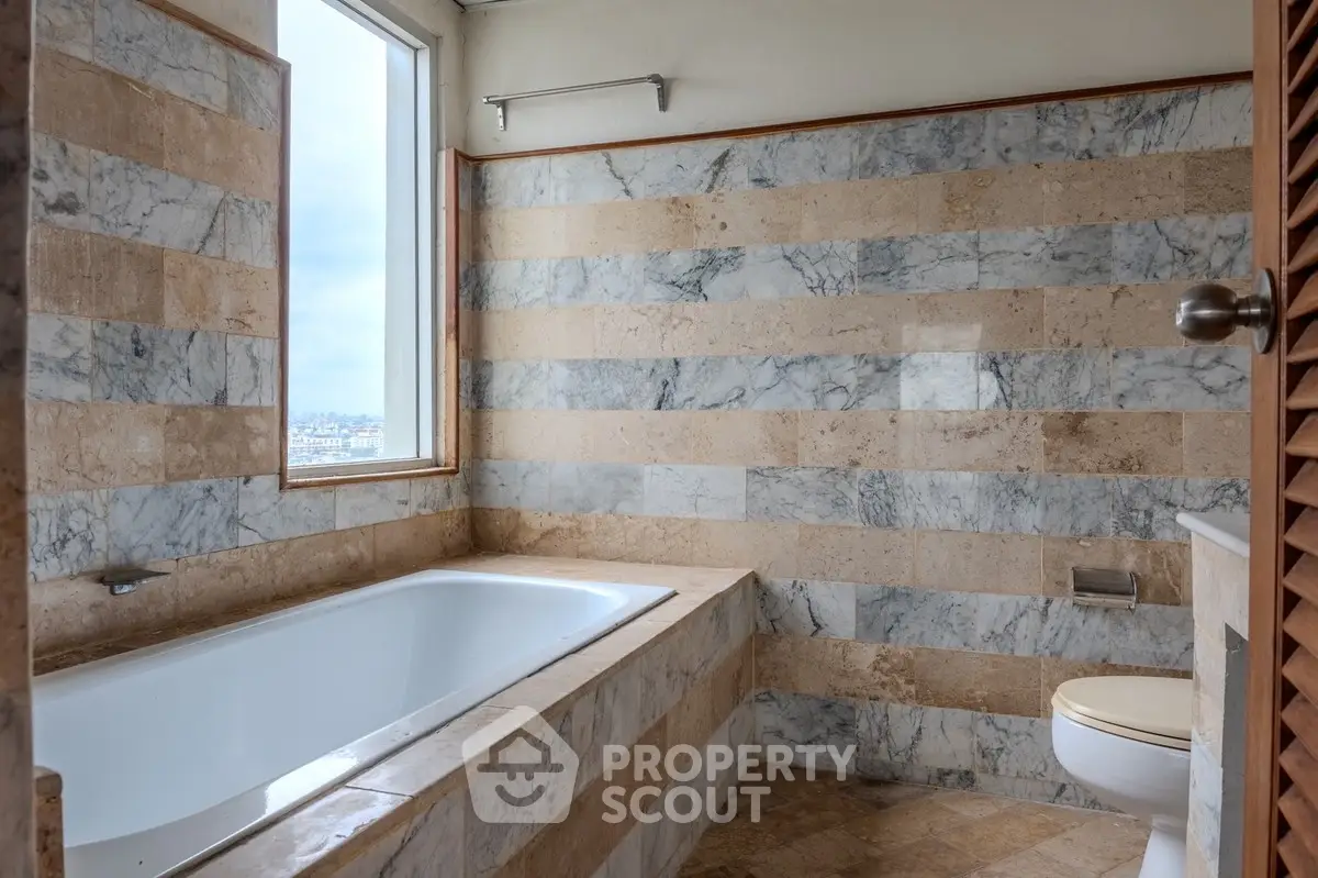 Luxurious marble bathroom with a spacious bathtub and city view window.