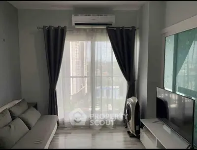 Modern living room with balcony view, sleek sofa, and flat-screen TV