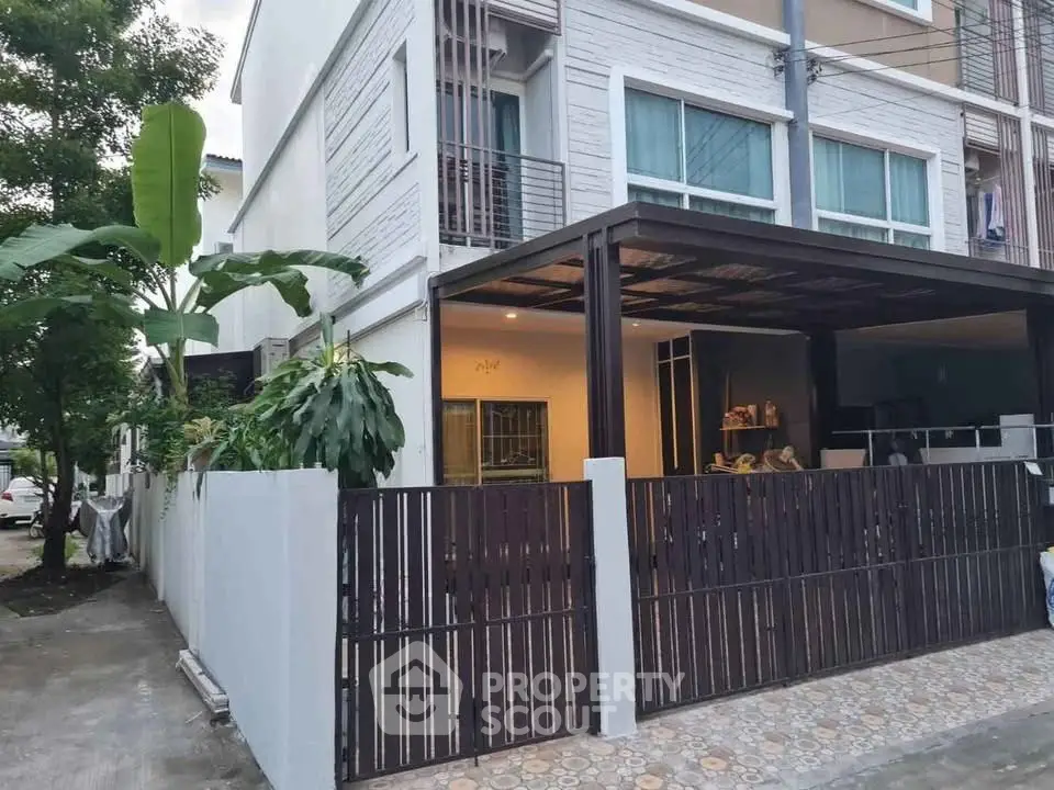 Modern townhouse exterior with gated entrance and covered parking area.