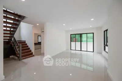 Spacious modern living room with sleek staircase and large windows