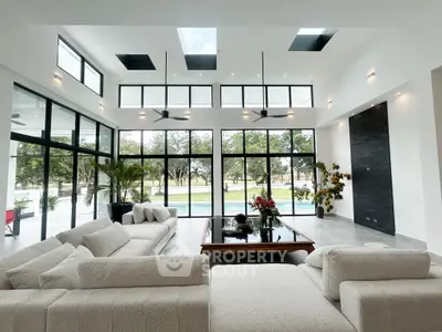 Luxurious modern living room with large windows and stunning garden view, featuring elegant sofas and stylish decor.