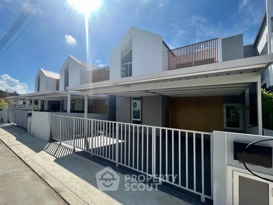 Modern townhouse exterior with sleek design and spacious carport under clear blue sky.
