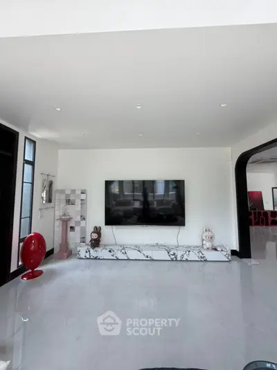 Spacious modern living room with sleek marble flooring and large wall-mounted TV, ideal for entertainment.