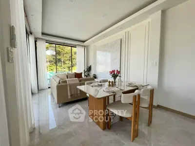 Elegant living room with dining area, featuring modern decor and large windows with scenic views.
