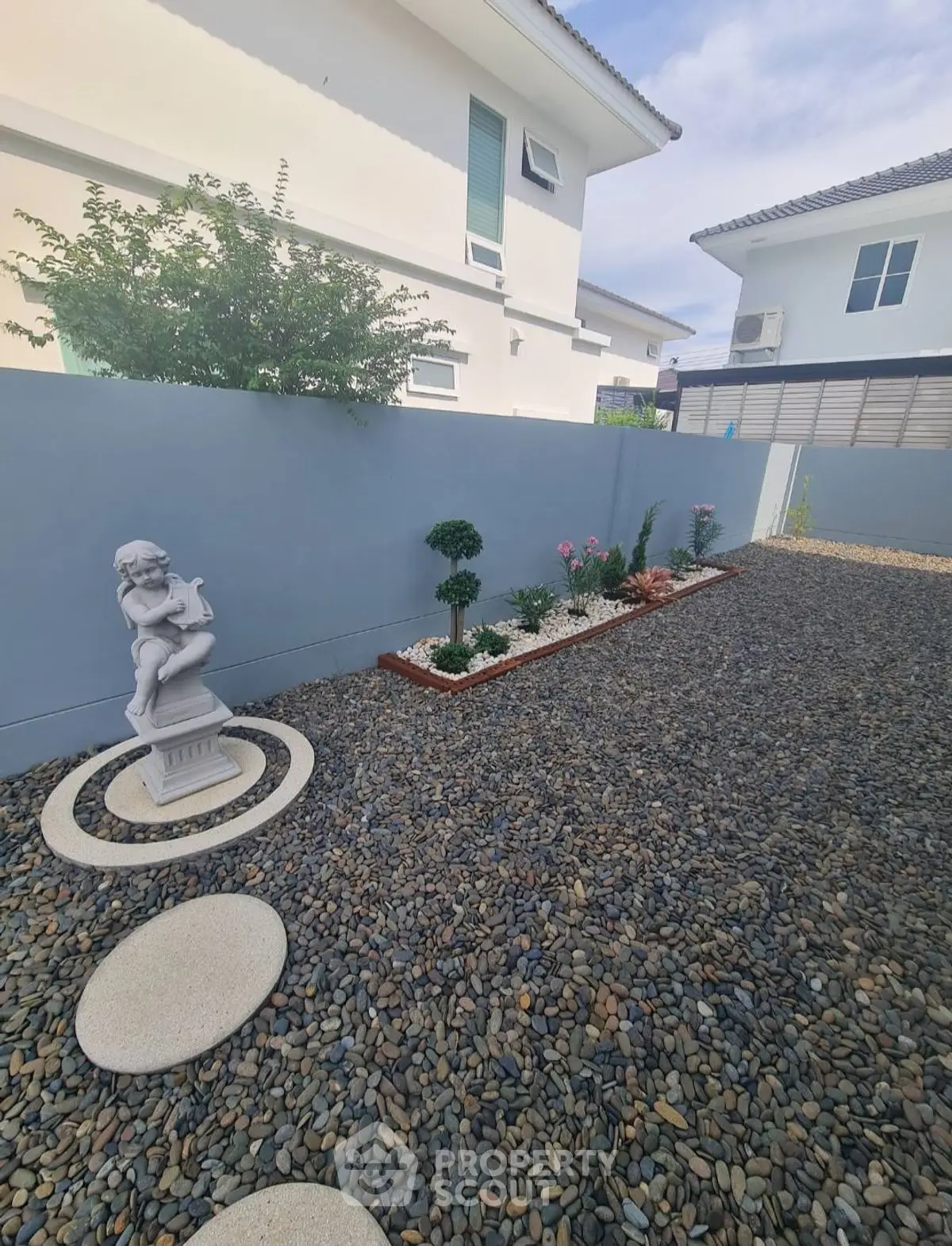 Charming garden area with decorative statue and modern landscaping in a residential property.