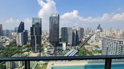 Stunning cityscape view from a high-rise balcony overlooking urban skyline and pool.