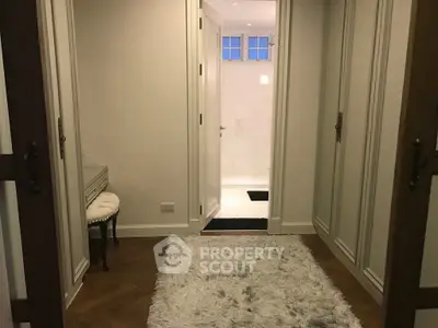 Elegant hallway leading to a luxurious bathroom with plush rug and classic decor.