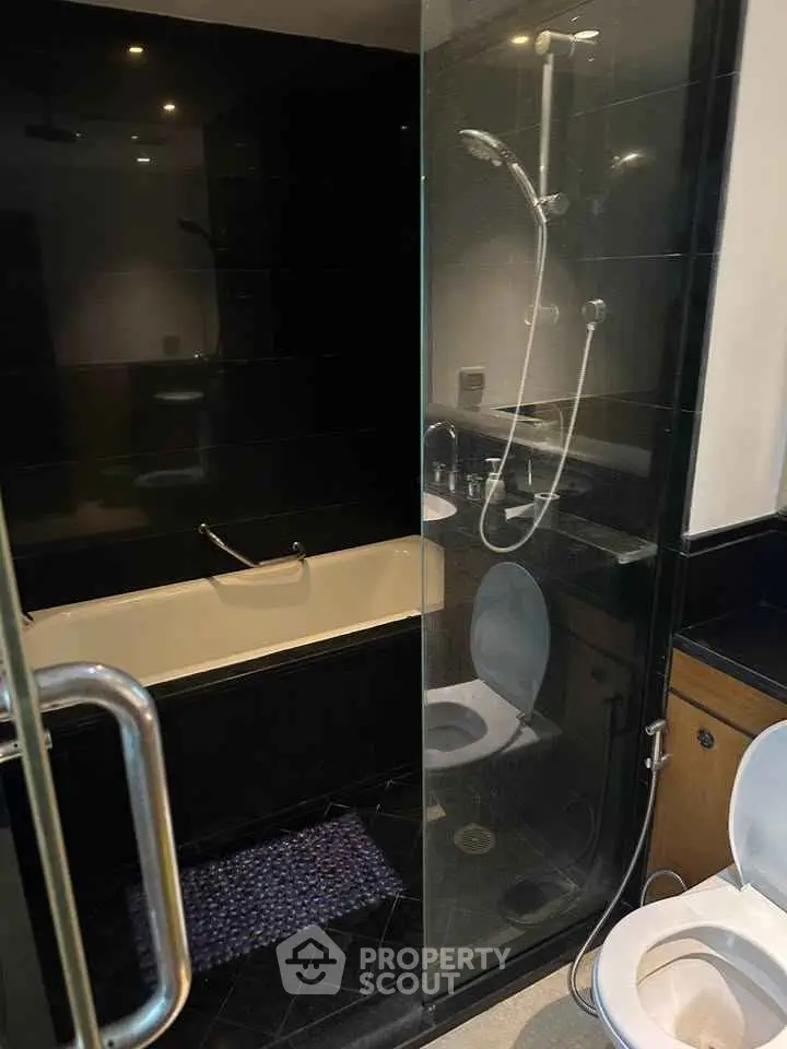 Modern bathroom with glass shower and bathtub in sleek design.