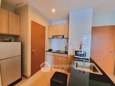 Modern kitchen with sleek wooden cabinets and stainless steel appliances in a cozy apartment.