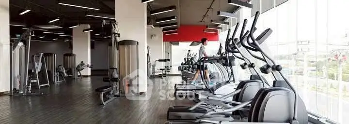 Spacious modern gym with state-of-the-art equipment and large windows offering natural light.